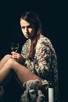 Studio portrait of a beautiful young brunette woman holding a bottle of white wine in retro colors