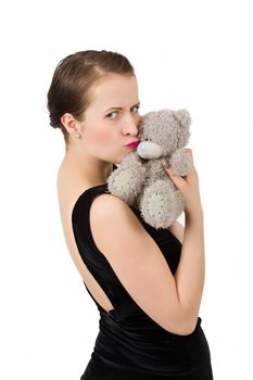 attractive smiling brunette holding teddy bear grimacing with peg on nose in a black dress, isolated on white