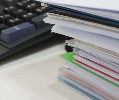 A pile of paperwork placed on a desk at office.                               