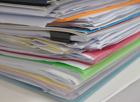 The stacked pile of papers on the desk in the office.                             