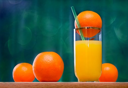 Fresh orange juice in the glass and some oranges on the table..