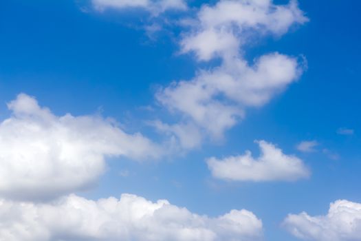 White fluffy clouds float on the blue sky in a clear sunny day.