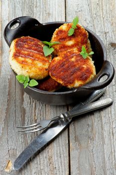 Delicious Homemade Meat Cutlets in Black Saucepan with Fork and Knife closeup on Rustic Wooden background