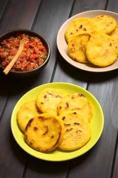 Two plates of arepas with Colombian hogao sauce (tomato and onion cooked) on the side. Arepas are made of yellow or white corn meal and are traditionally eaten in Colombia and Venezuela (Selective Focus, Focus on the first arepas)