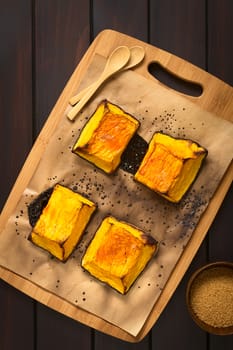 Baked pumkin pieces with caramelized sugar on top, a traditional autumn snack in Hungary, photographed overhead on dark wood with natural light