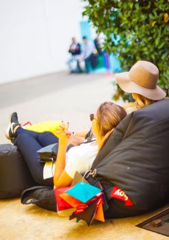 MILAN, ITALY - APRIL 16: Two young girls lie down on pouf at Tortona space location during Milan Design week on April 16, 2015