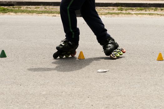 Roller skater practicing slalom along a line of cones on asphalt.