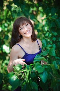 beautiful girl on a background of green leaves in summer park.