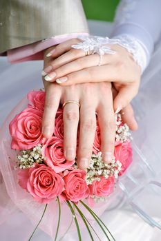 hand the bride and groom with the rings lying on the bridal bouquet.
