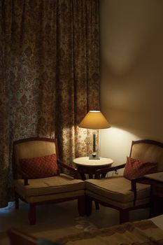 desk lamp and two chairs in the room of hotel.