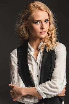 Beauty blond woman  in a black suit and white shirt on a gray background