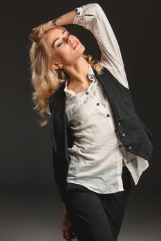 Beauty blond woman  in a black suit and white shirt on a gray background