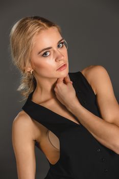 Beauty blond woman  in a black suit  on a gray background