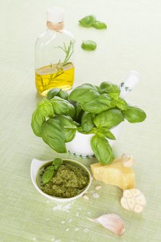 Green pesto background. Extra virgin olive oil, green pesto, parmigiano and fresh basil herbs on bright green background. Organic mediterranean eating. 