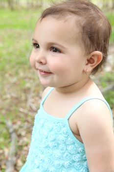 Beautiful brunette toddler girl playing outside in the field