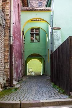 Sighisoara, Romania - June 23, 2013: Old stone paved street with arches from Sighisoara fortress, Transylvania, Romania