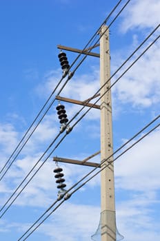 High electricity post and cable line with blue sky as background.