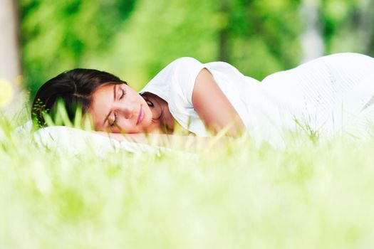 Beautiful young woman sleeping on grass outdoors