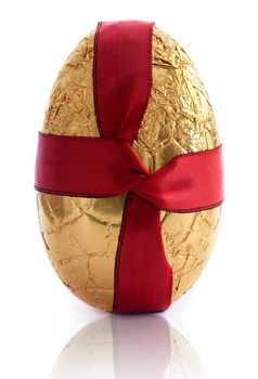 Gold easter egg covered in foil with a red silk ribbon