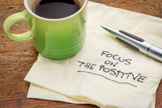 focus on the positive - motivational words handwritten on a napkin with a cup of espresso coffee