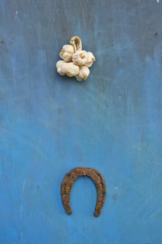 old rusty horseshoe and garlic bulb bunch on wooden house wall