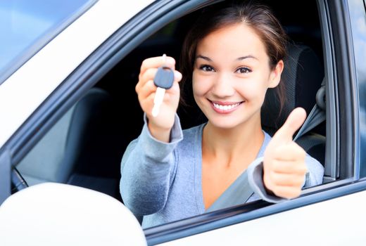 Happy girl in a car showing a key and thumb up gesture