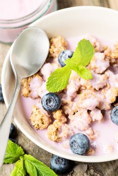 Fresh blueberry yogurt with granola and mint on a background