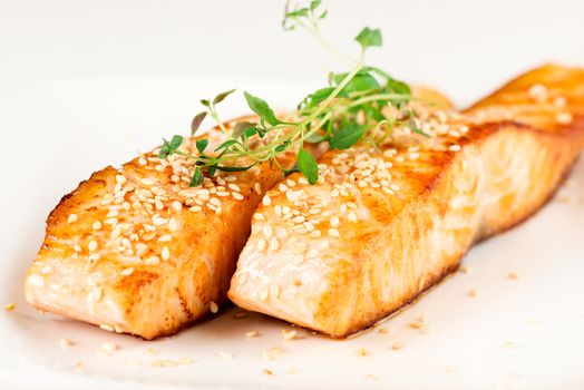 Grilled salmon, sesame seeds  and marjoram on white plate. Studio shot