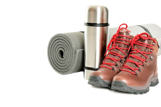 Hiker equipment: pair of mountain boots, thermo flask and sleeping mat on white background