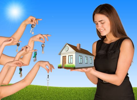 Businesswoman holding house with set of hands offering keys on natural background