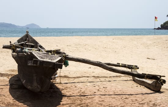 Old fishing boat standing on the sandy beach. India, Goa.