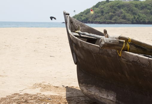 Old fishing boat standing on the sandy beach. India, Goa.