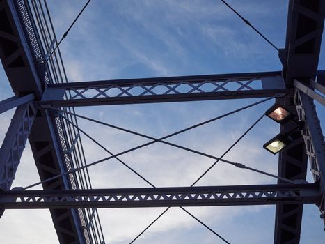 Detail shot of an historic gray painted Dutch riveted truss bridge against a blue sky.