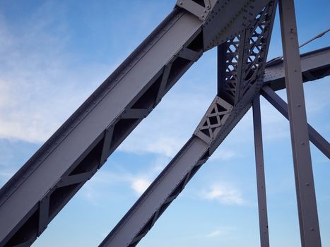 Detail shot of an historic gray painted Dutch riveted truss bridge against a blue sky.