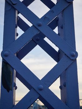 Detail shot of an historic gray painted Dutch riveted truss bridge against a blue sky.