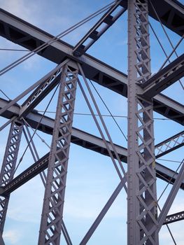 Detail shot of an historic gray painted Dutch riveted truss bridge against a blue sky.