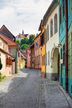 Sighisoara, Romania - June 23, 2013: Stone paved old street with colored houses from Sighisoara fortresss, Transylvania, Romania