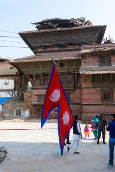 KATHMANDU, NEPAL - MAY 14, 2015: A man carries a large Nepal flag on Durbar Square, a UNESCO World Heritage Site.