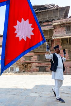 KATHMANDU, NEPAL - MAY 14, 2015: A man carries a large Nepal flag on Durbar Square, a UNESCO World Heritage Site.