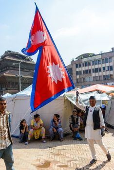 KATHMANDU, NEPAL - MAY 14, 2015: A man carries a large Nepal flag on Durbar Square, a UNESCO World Heritage Site.