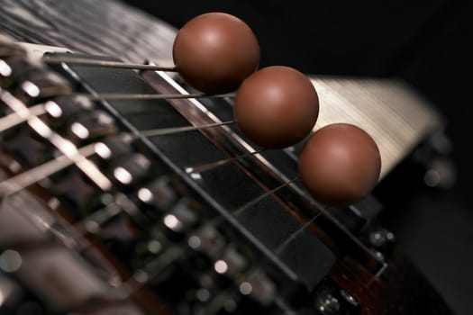 three chocolate eggs placed on the strings of a guitar