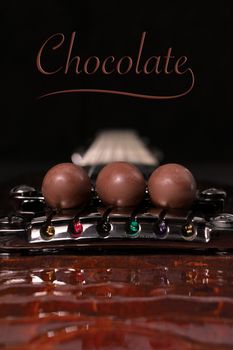 three chocolate eggs placed on the strings of a guitar