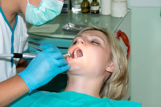 Close-up of young female having her teeth cleaned at dentist office