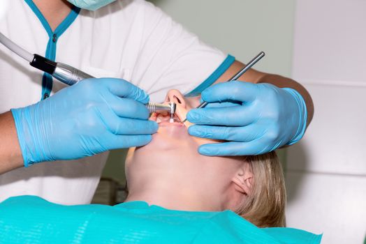 Close-up of young female having her teeth cleaned at dentist office