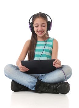 Beautiful pre-teen girl using a tablet computer and headphones.