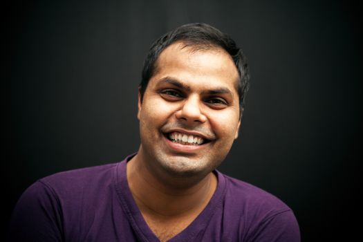 Portrait of handsome indian man laughing in studio