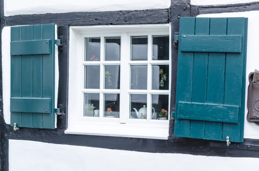 Shutters in front of a window of a half-timbered house with stopes.