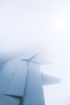 Window view of wing of an jet airplane with deep blue sky and the sun in the background