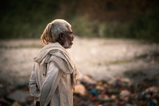 Portrait of poor old Indian man dressed in the old dirty cloths living in a shack