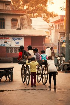 Happy Indian kids playing with wheel cart in evening at Bithoor Temple, near The Bank of Ganga river, Kanpur, India, 23 November 2014.